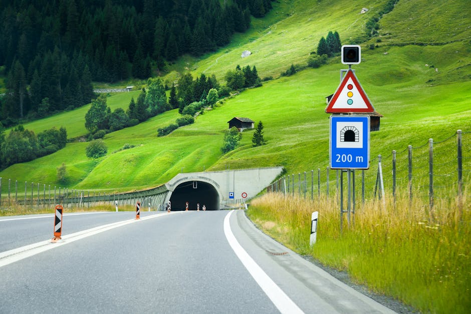 View of a road in Zürich, Switzerland leading to a mountain tunnel with lush greenery.