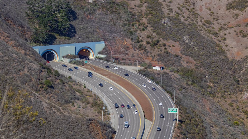 Aerial photo capturing traffic flowing through scenic highway tunnels surrounded by hills.